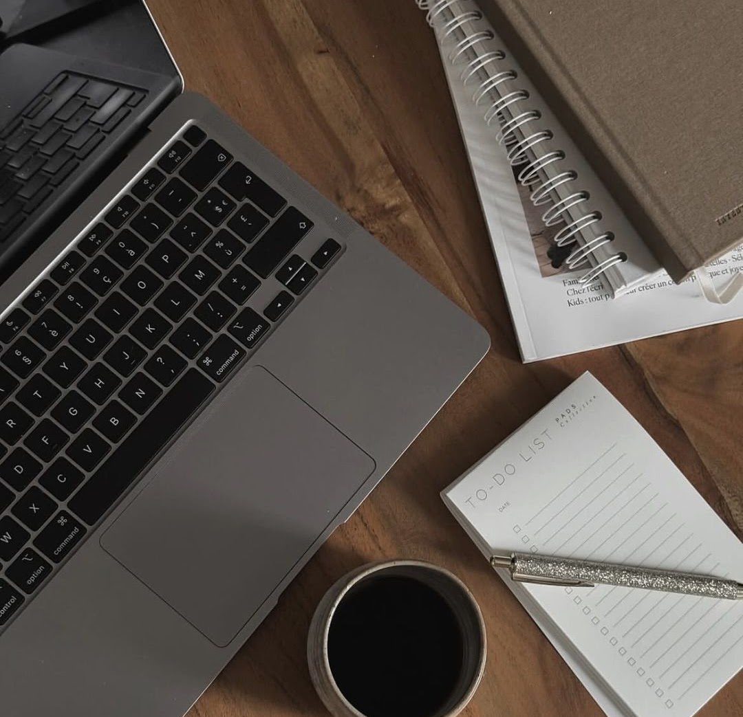 Un bureau avec ordinateur, carnets et café